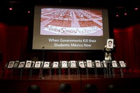 Fig. 8. A row of chairs on a stage holding headshots representing the missing students of Ayotzinapa.