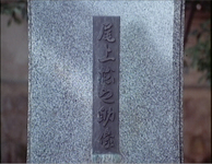 Closeup of the grave of Onoe Matsunosuke, the first movie star in Japan, has cast iron calligraphy with his name rendered in calligraphy.