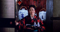 A woman enters through a doorway carrying a tray of sake bottles, calligraphy visible on the bottles, barrels, and signs..