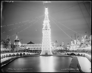 A black-and-white photograph of the Electric Tower at Luna Park amusement park at night, brilliantly lit up with thousands of lightbulbs laid out in fanciful shapes and patterns.
