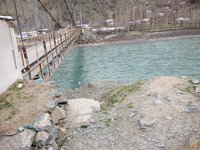 Image of a metal suspension bridge that spans the river that creates a natural division along the border between Tajikistan and Afghanistan in the districts of Tajik Shughnan and Afghan Shughnan.
