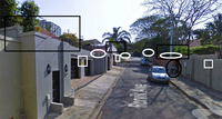 An image of a road in the Berea neighborhood of Durban, with security features like electric fences, cameras, contracted security companies, and an in-person guard, each feature framed in black or white boxes or circles.