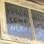 A photograph of a dirty window where someone has written “send nudes”