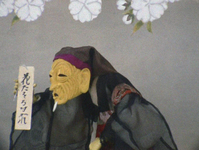 A puppet dressed like an old monk holds up a message with calligiraphic writing that warns people not to break branches.