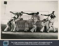 In this photograph of the biomechanics exercise “The Horse,” also called “Three as a Horse,” one actor holds on to the shoulders of another while a third, one leg aloft, “rides” the horse formed by the lower two.