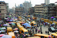 Photograph of yellow buses lining a street busy with people