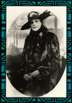 Dunbar sits in three-quarter view with a slight smile, hands in her lap. She wears a fancy broad-brimmed hat and a long coat with a collar, wide cuffs, and large buttons.