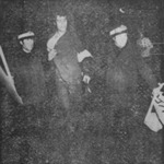 2 anonymous helmeted policemen grip a tall, dark Mizrahi protestor in a suit jacket by the arm as they drag him off to be arrested.