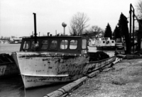 A photograph of the left side of a fisherman's boat sitting at the dock, from the front.