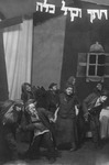 Black-and-white photograph of a group of actors in exaggerated poses with Hebrew letters hanging above them