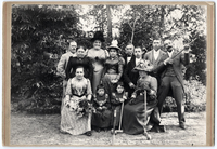 Posed group photograph of ten adults and two children outdoors, sporting croquet equipment.