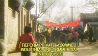 A propaganda banner with calligraphic characters stretches over a street as a group walks toward the camera. At the bottom is an electronically rendered English subtitle reading, "Reform privately-owned industrial and commerical enterprises."