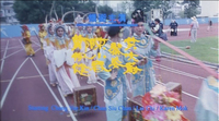 Yellow calligraphy, with yellow calligraphy and blue roman text, over a background of a festival procession on a sports track.