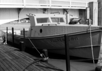 A photograph of the right side of a fisherman's boat, named Florence-H-11, sitting at the dock, from the front.