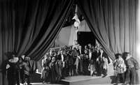 Photograph from the end of Princess Turandot. The actors hold the costume pieces they have just taken off while peeking out directly at the audience from the partially open curtain that the forestage servants pull back.
