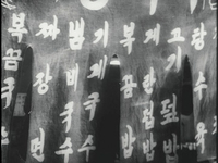 White calligraphy is printed on a noren covered in a yatai food stall, as protagonist Cheolho approaches from behind it.
