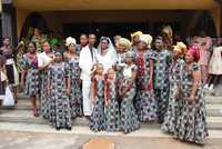 Family members dressed in aso ebi pose for photos around bride and groom.