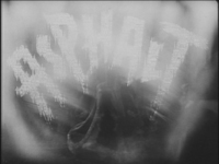 Highly stylized lettering of the title is superimposed on a close-up of an asphalt tamper. It is in white, block letters with ragged edges.