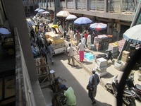 Kano market scene with men unloading wax-print textile bundles.