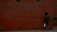A character writes graffito on a red wall: "Samo as an alternative to..."