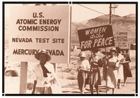 Seven women protesting by the Nevada Test Site sign. All wear large sun hats and carry signs saying “WOMEN Strike FOR PEACE” and “WE OPPOSE NUCLEAR TESTING BY ANY NATION.”