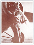 Earhart and propeller close up. With a soft smile and short, wavy hair, Earhart stands with one hand on the propeller. She wears a tailored pantsuit with large lapels and a tie.