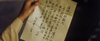 A person holds a letter, with black calligraphy.