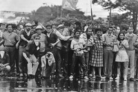 A photograph of Philippine opposition leaders standing in a row with interlocked arms at a protest against the Marcos administration at the Welcome Rotunda, Quezon City, on September 27, 1984. They are all wet and staring at some military personnel off camera, after having been sprayed with water by water cannons. Photo credit: Jacinto Tee.