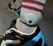 Photo of an electronic monitoring ankle bracelet on a peron's ankle, situated atop their sock.
