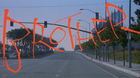 A film still of red calligraphic text over the background of an empty four lane street.