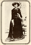 Starr is posed in a studio, wearing a full-length, long-sleeved dress and a broad-brimmed hat and holding a revolver. Another revolver sits in a holster around her waist. The border of the photograph replicates a rope.