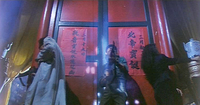 A low angle of Chow Ying-kit and gunmen in front of red doors to a temple.