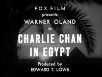 Title screen for "Charlie Chan in Egypt" with production credits above and below, all in white English type, superimposed over a black and white image of a palm tree and pyramids in silhouettes.