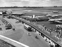 Men, women, and children strolled and sat along an elevated walkway watching airplanes take off and land.