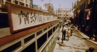 A city street and traffic during the day, with calligraphy visible on signs.