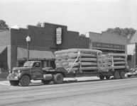 A black-and-white photograph of Grumman canoes loaded on a truck.