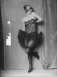 A 1919 photograph of Anita Berber as a Pritzel doll taken by Atelier Madame d’Ora shows the dancer wearing a black lace bustier, a see-through black tulle skirt, and black tights. She is standing on one leg, while the other is bent and pointed. Her arms are bent and raised above her head, while her face is turned to the side, eyes closed, with an open-mouth smile.