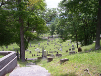 Color photograph of Mount Hope Cemetery landscape from the top of a hill, with view of monuments and trees.