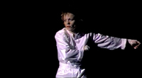 Figure 3. Laurie Anderson, dressed in a white silk jumpsuit, touches sensors in the suit to trigger percussive sound samples, thus becoming the musician and the instrument simultaneously.