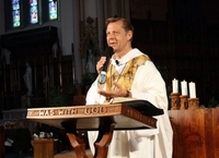 Image of a man delivering a sermon at a podium with words engraved into it: “WAS WITH GOD”