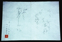 A film still of a paper with thin calligraphic text on it, with a red seal in the bottom left corner.
