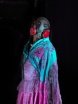 A still photograph shows Maxi Mamani dressed in drag as Bartolina Xixa. Xixa wears a pink pollera, a turquoise shawl, and an industrial gas mask to represent the toxic air at the Hornillos garbage dump.