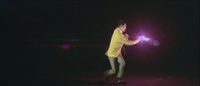 In a brief color insert that interrupts a monochrome sequence, Tetsu in a brilliant yellow jacket twists around and fires off three shots, with both gun and gunsmoke taking on a brilliant purple tint due to the use of colored light filters. The background of the shot is black and featureless but for the areas reflecting the flashing purple light.
