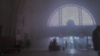 Sepia-­toned image of figures crossing a train station of the mid-­twentieth century