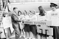 Photograph of Reagan being presented with an oversized key to the Governor’s Mansion by seven Reagan Girls, dressed in matching outfits complete with red berets.