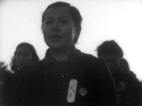 Watanabe wears a sticker with black calligraphy, in black and white cinematography.