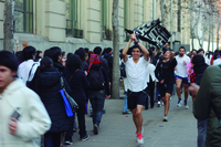 Fig. 6. While people go about their business in the city, young protesters run carrying a flag to draw attention to the need for public education.