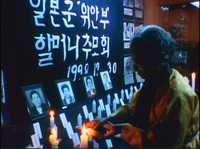 Film still from My Own Breathing  shows During a memorial service, a survivor lights a candle for former 'comfort women' who have passed away.