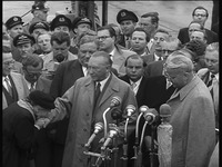 An elderly woman, described in the documentation of the photograph as the mother of a POW, gratefully kisses Adenauer’s hand during remarks to the press. Adenauer had just returned from Moscow to Cologne/Wahn airport with the Soviet promise that the POWs would be released.