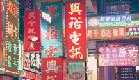 A color photo of a city street focused on numerous signs with calligraphic text.